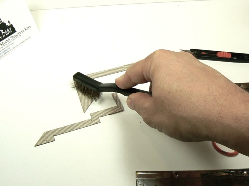 Distressing the loading dock on Curtis Bros Plumbing Supply Kit with a steel brush.